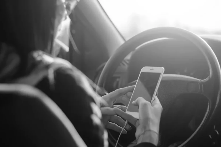 Frau sitzt mit dem Handy in der Hand in einem Auto