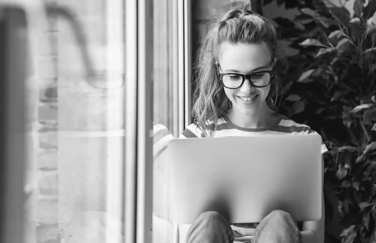 Frau arbeitet lachend am Laptop